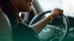 Pessoa dirigindo um carro Hyundai, sorrindo enquanto segura o volante, ilustrando confiança e segurança na direção, demonstrando a importância de saber como checar veículos e o histórico do motorista.