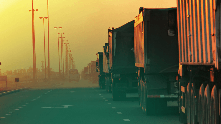 Caminhões trafegando na estrada no por do sol.